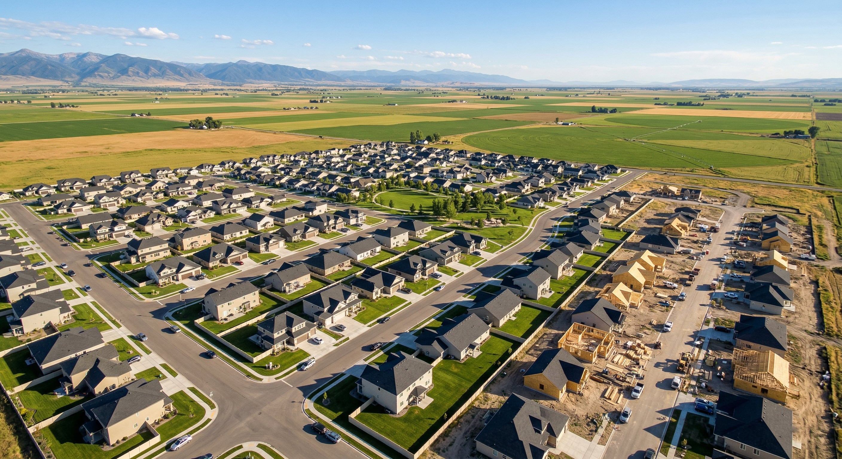 Aerial view of new homes in Ammon, Idaho with farmland and mountains in the background
